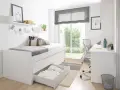 Habitación estrecha y alargada con cama blanca, escritorio y silla. Ventana grande con vistas al jardín.