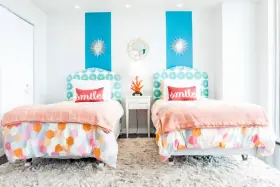 Dos camas gemelas en habitación pequeña, con cabeceros estampados y colchas naranjas. ¡Una solución genial para como poner dos camas en una habitacion pequeña!