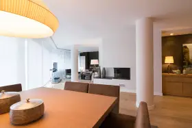 Comedor y salón modernos tras reforma piso pequeño. Mesa de madera, chimenea y mobiliario elegante.